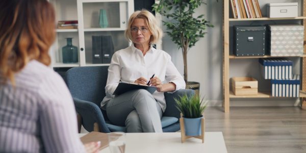 a woman sitting in a chair talking to another woman